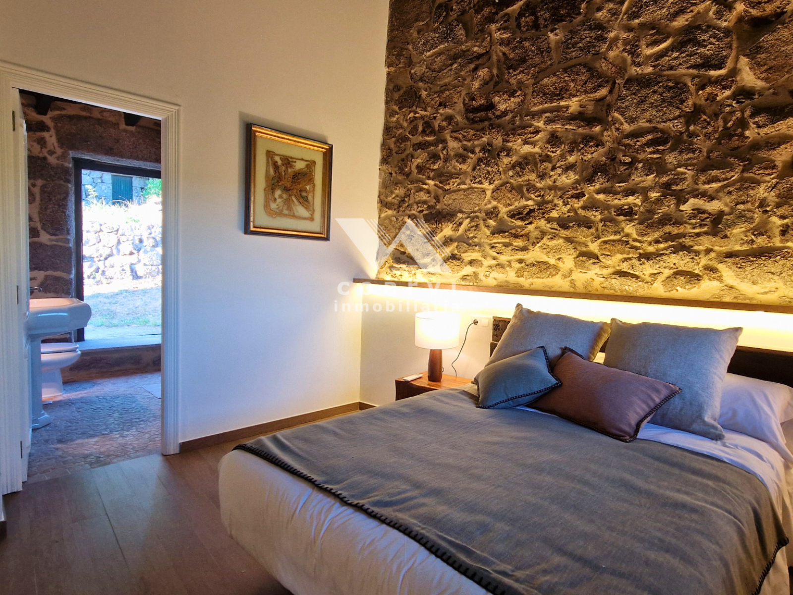 Dormitorio doble con pared de piedra y puerta exterior en casa de Lobios