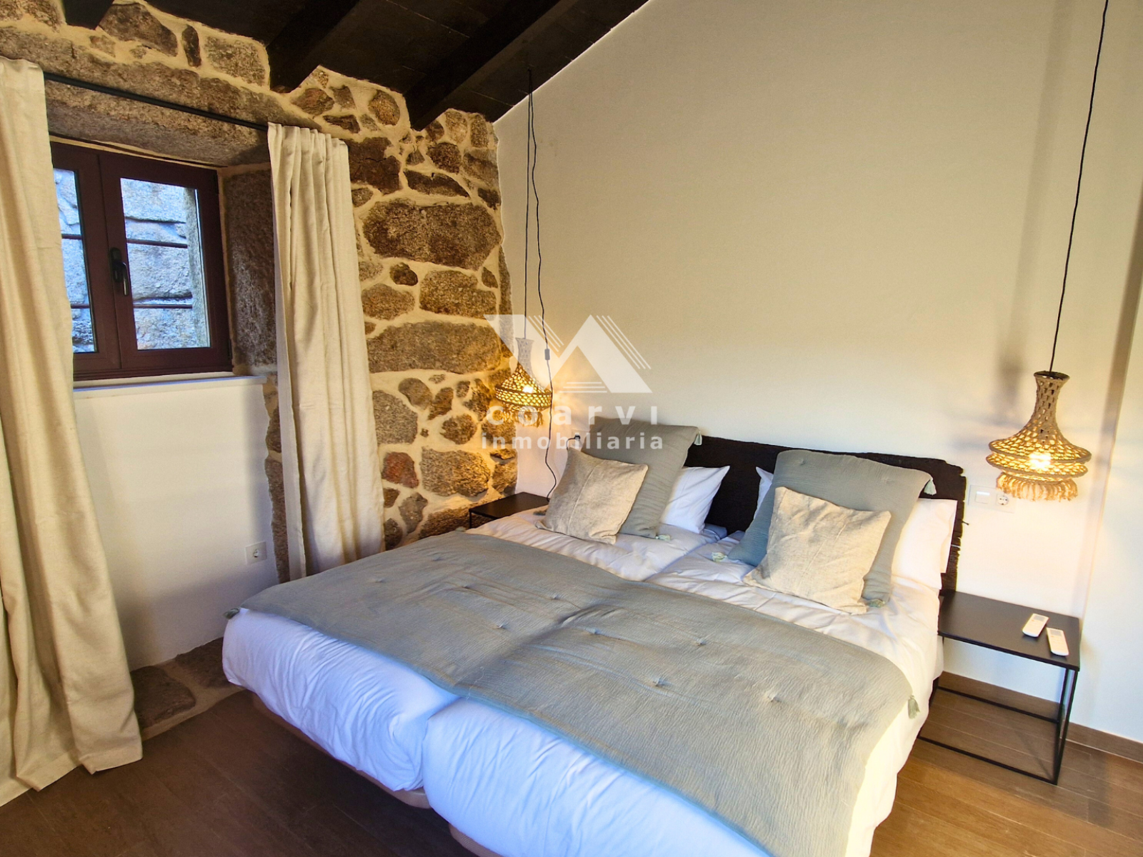 Dormitorio doble con pared de piedra y ventana de madera