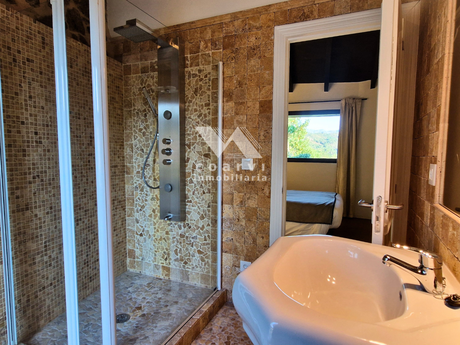 Baño con ducha y paredes de piedra en casa de Lobios