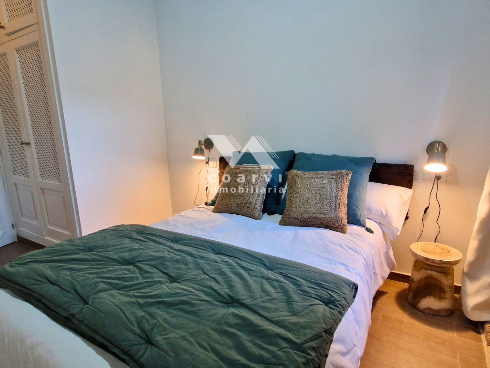 Cama doble con mesillas e iluminación en dormitorio de la vivienda