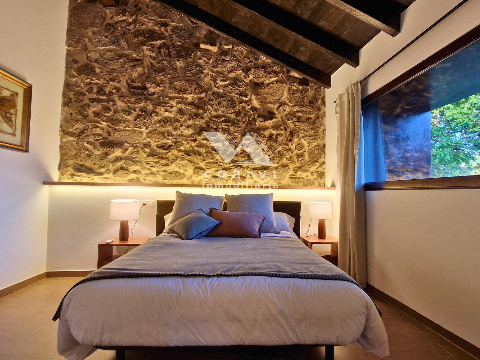 Dormitorio doble con pared de piedra y ventana en casa de Lobios