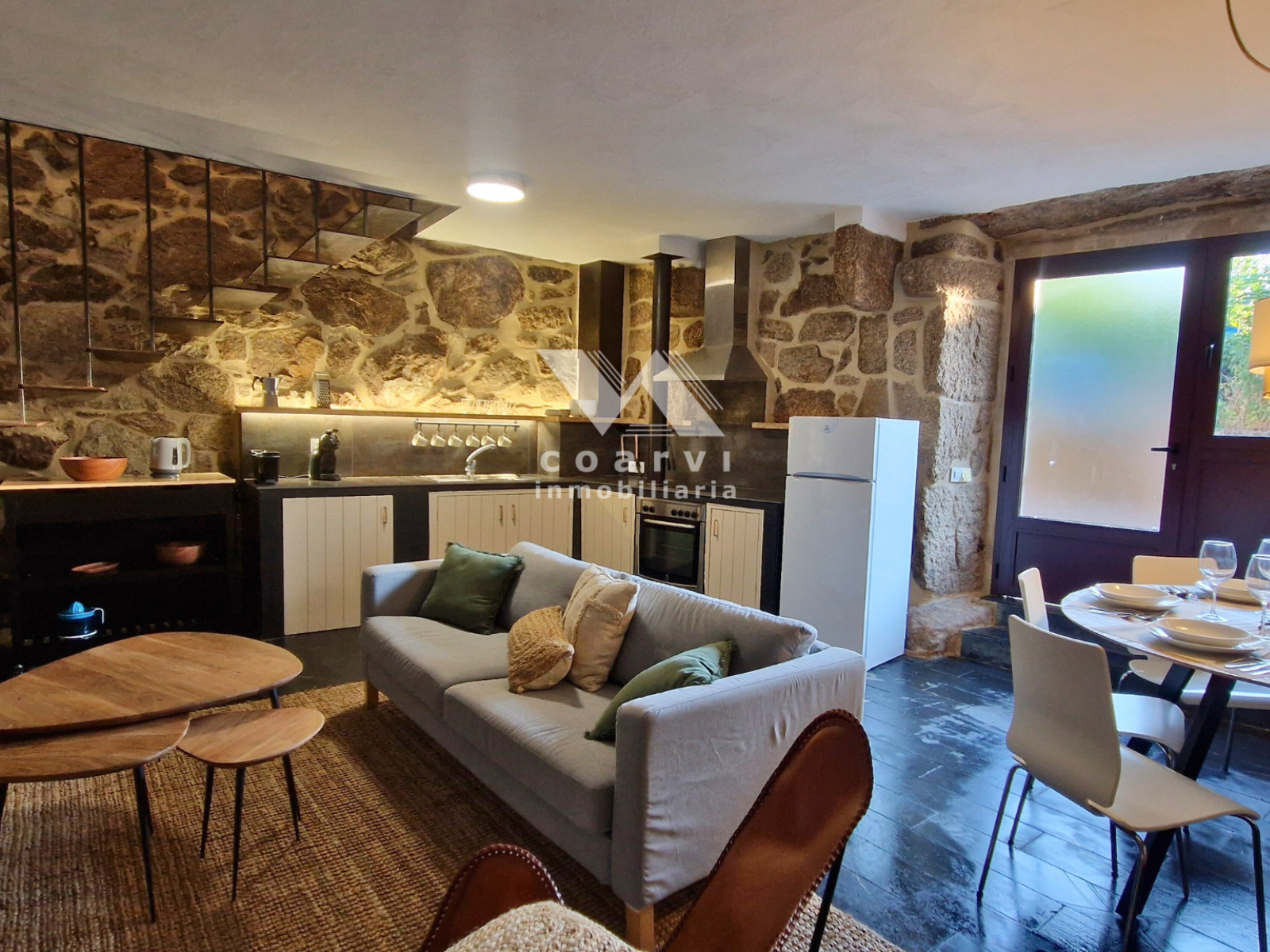 Interior de salón con cocina abierta en vivienda de piedra en Lobios