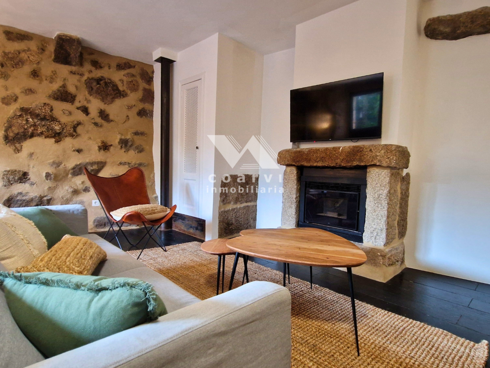 Salón con chimenea y pared de piedra de casa en venta en Parada de Ventosa, Lobios